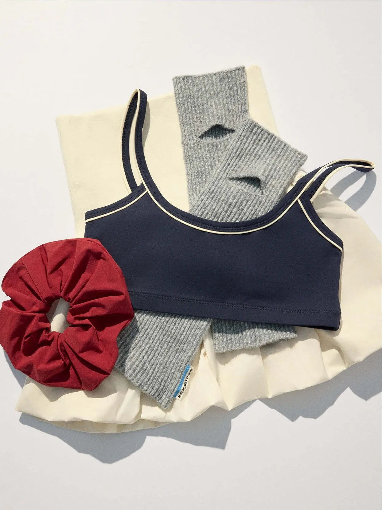Flat lay: navy strappy top, grey ribbed leg warmers, cream skirt and a red chouchou