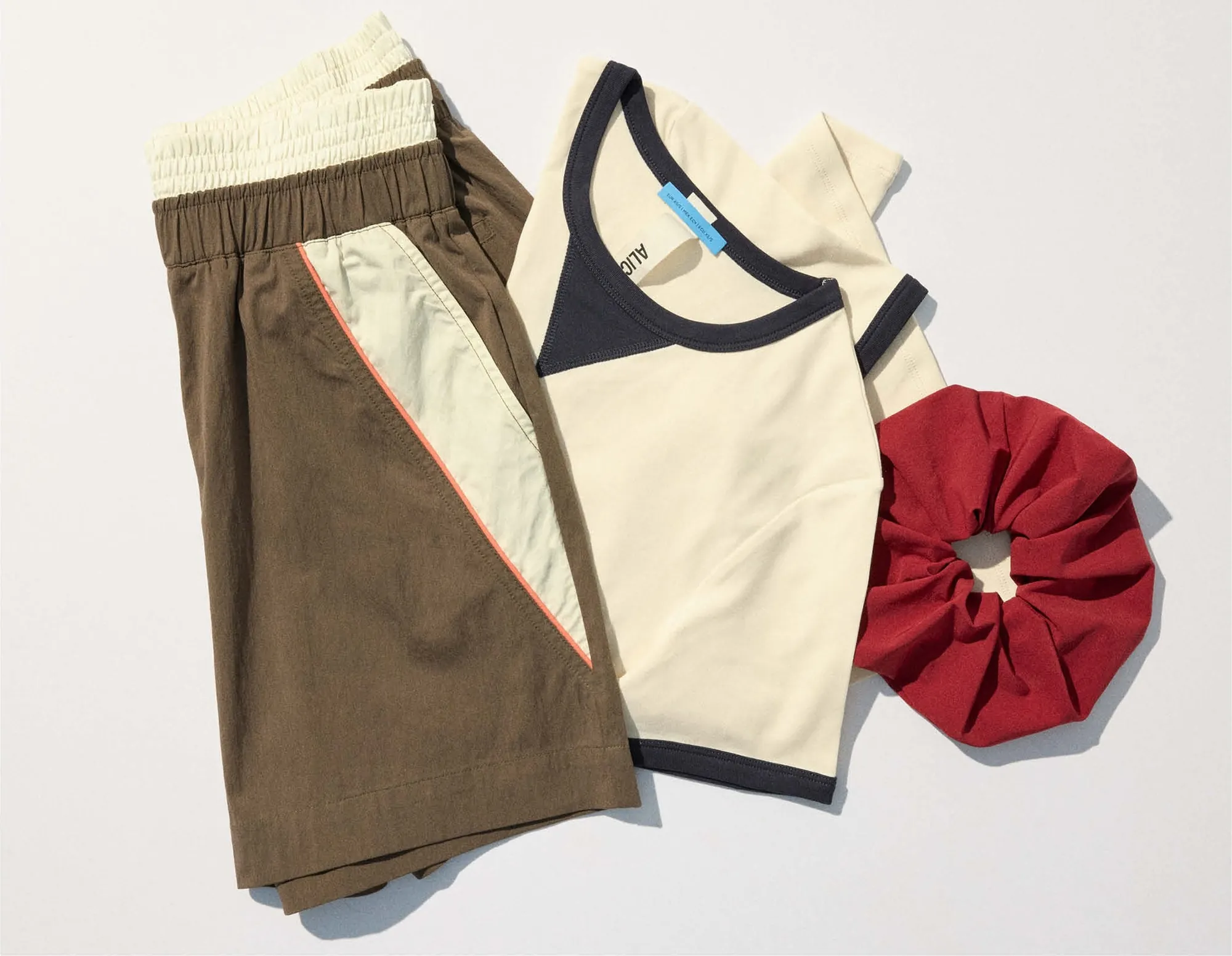 Flat lay: brown shorts, the cream contrast t-shirt and a red chouchou
