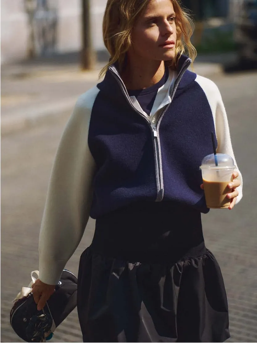 Pushing a bicycle in the colour-block windbreaker, phone in hand
