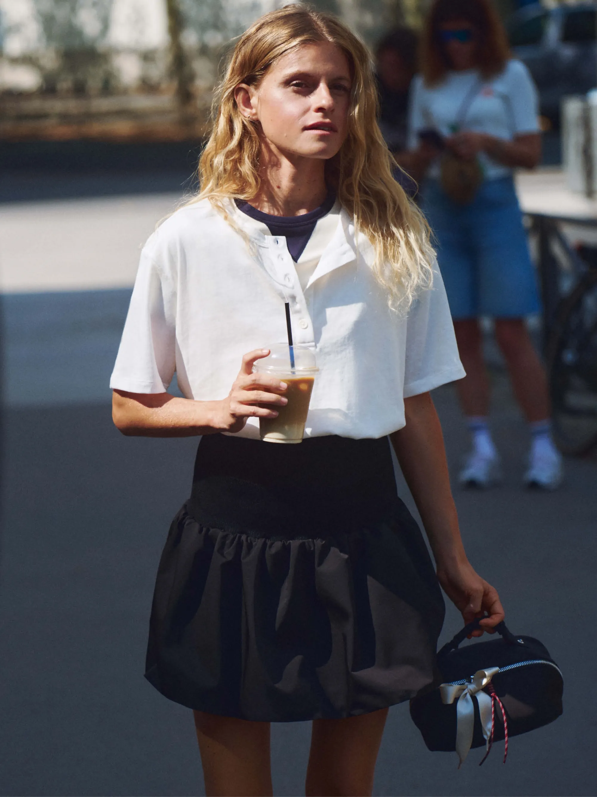 On the street in the white cotton t-shirt and black balloon skirt, the toiletry bag in hand