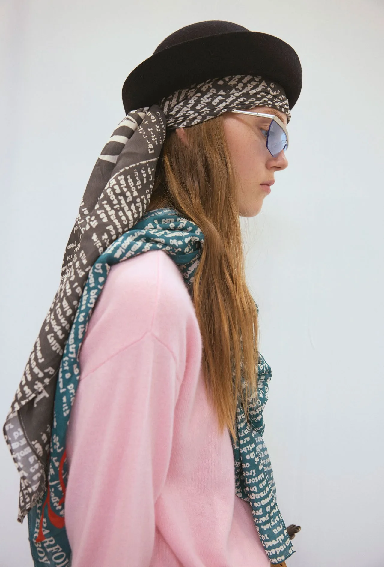 Profile with a newsprint scarf wrapped under a black hat