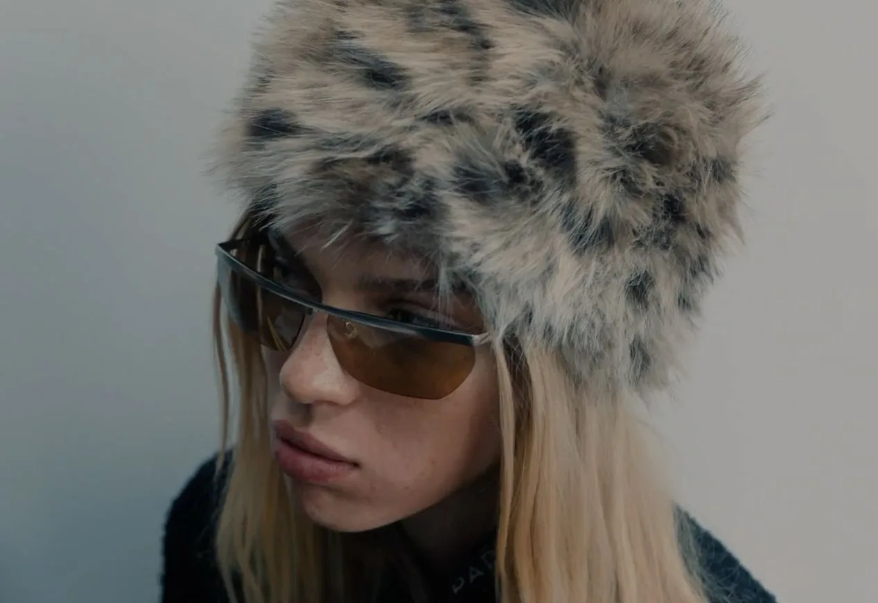 Close portrait in a leopard-print faux fur hat and visor sunglasses