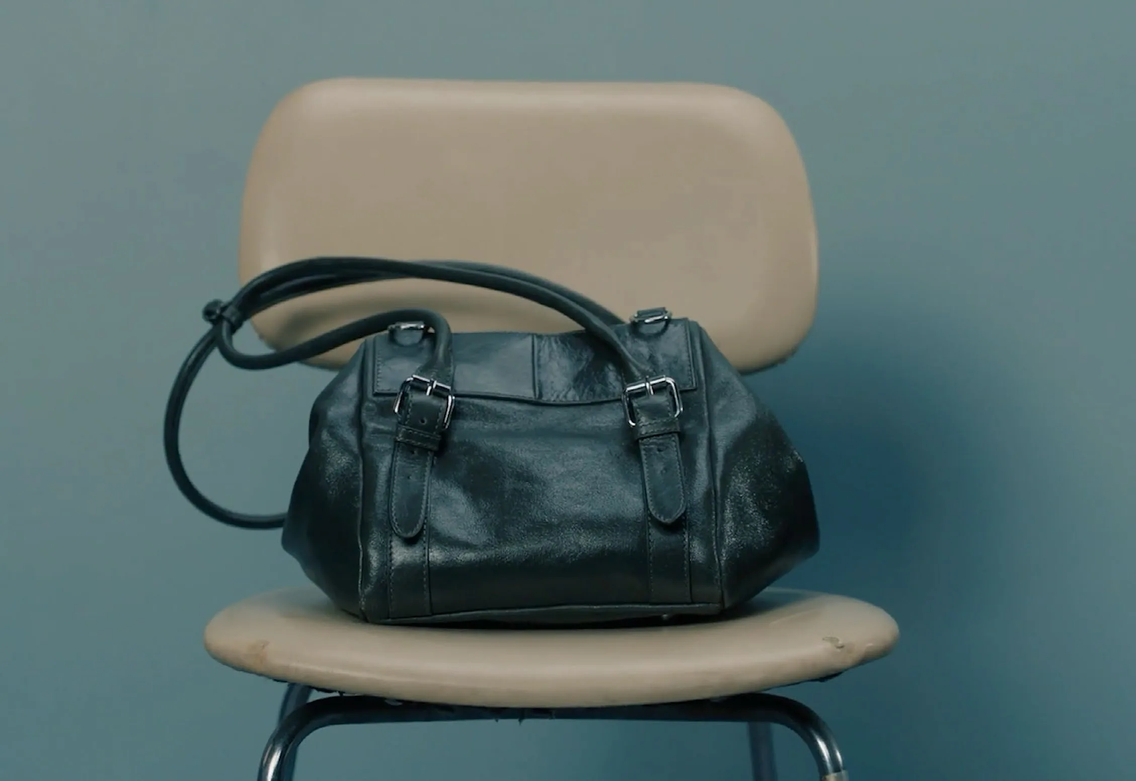 Green leather holdall resting on a studio chair