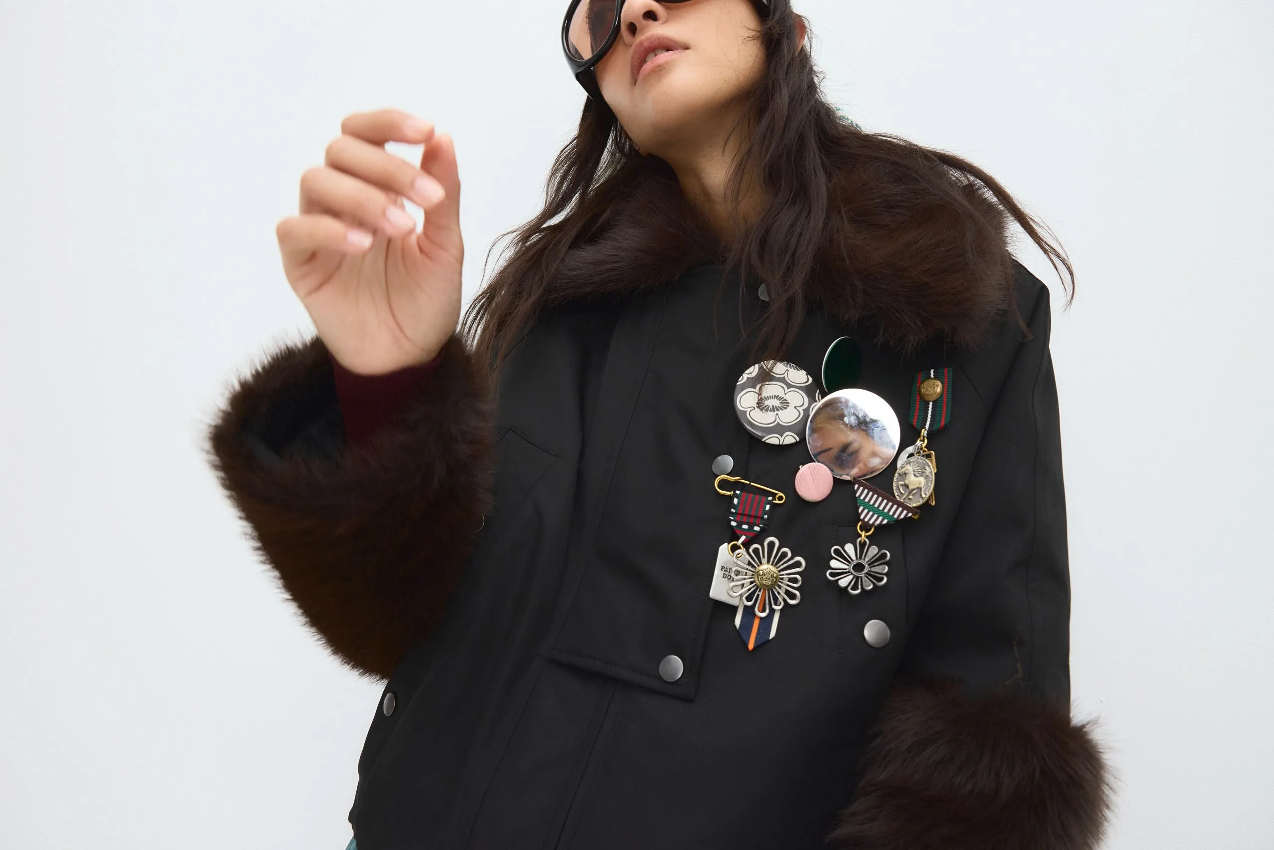 Black jacket with fur cuffs, covered in badges and brooches