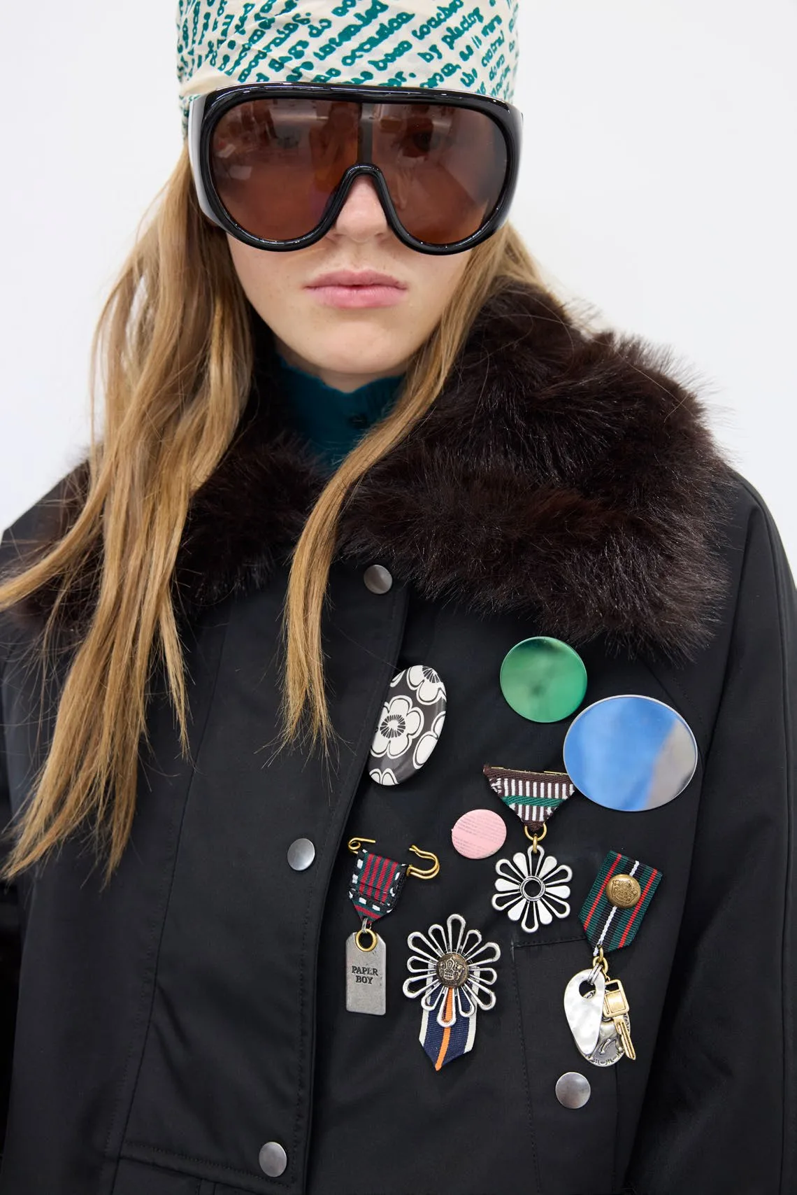 Ski-style goggles and a fur collar, badges catching the light