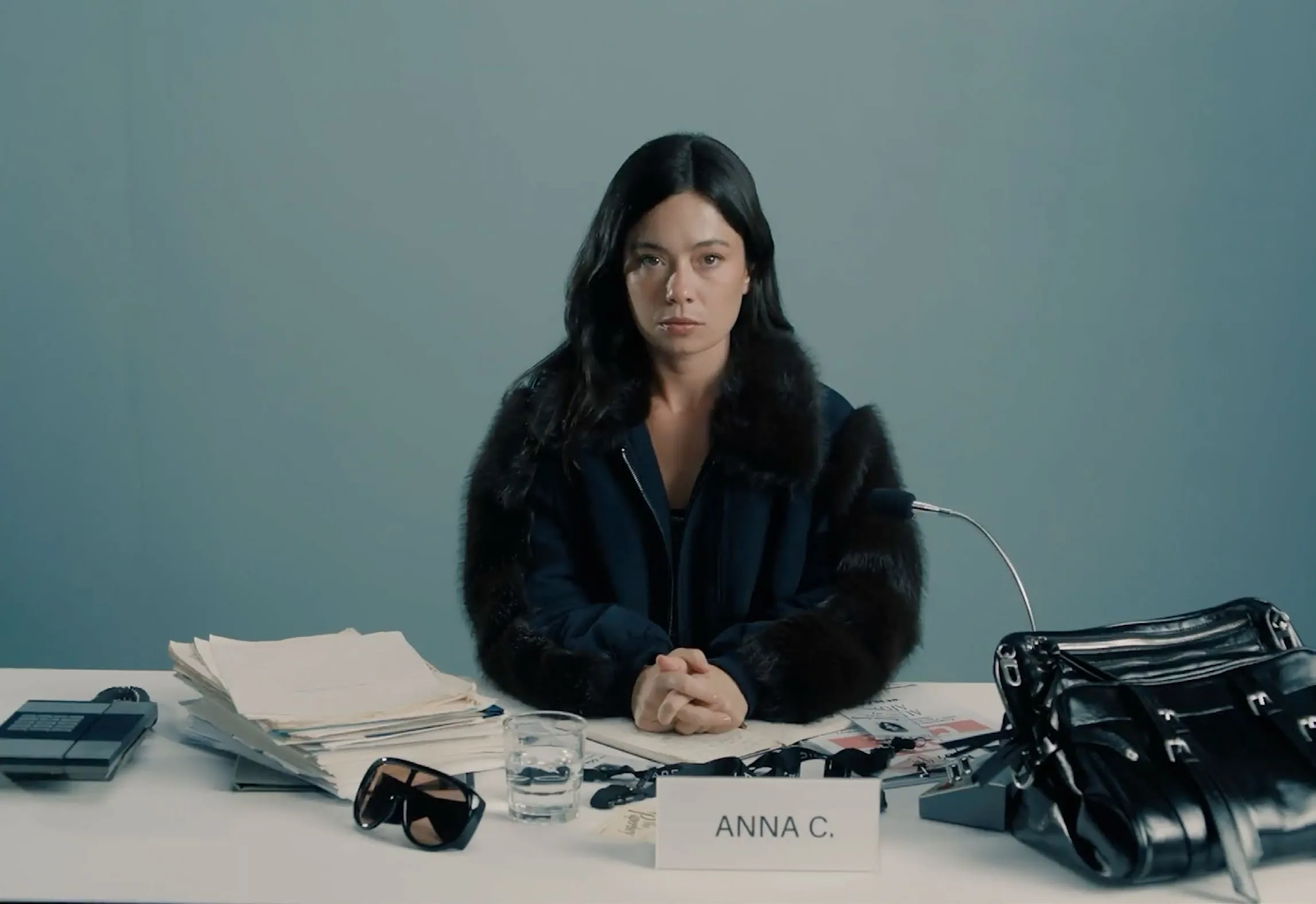 Final casting tape: Anna C. behind a desk stacked with the season's bags